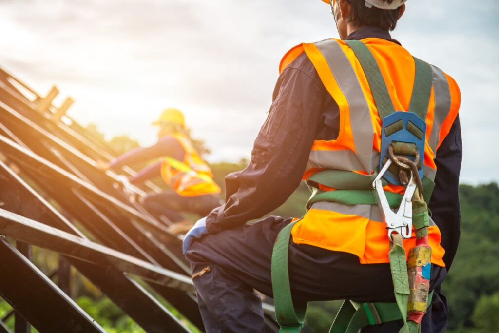 safety body construction Working at height equipment. Fall arrestor device for worker with hooks for safety body harness on selective focus. Worker as in construction background.
