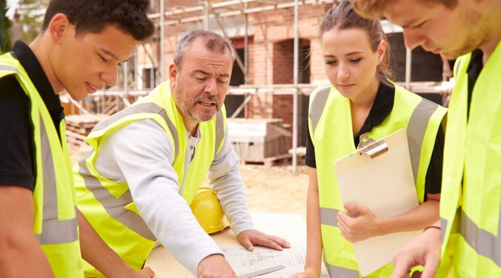 3 team members discuss workplace safety topics on a construction site.