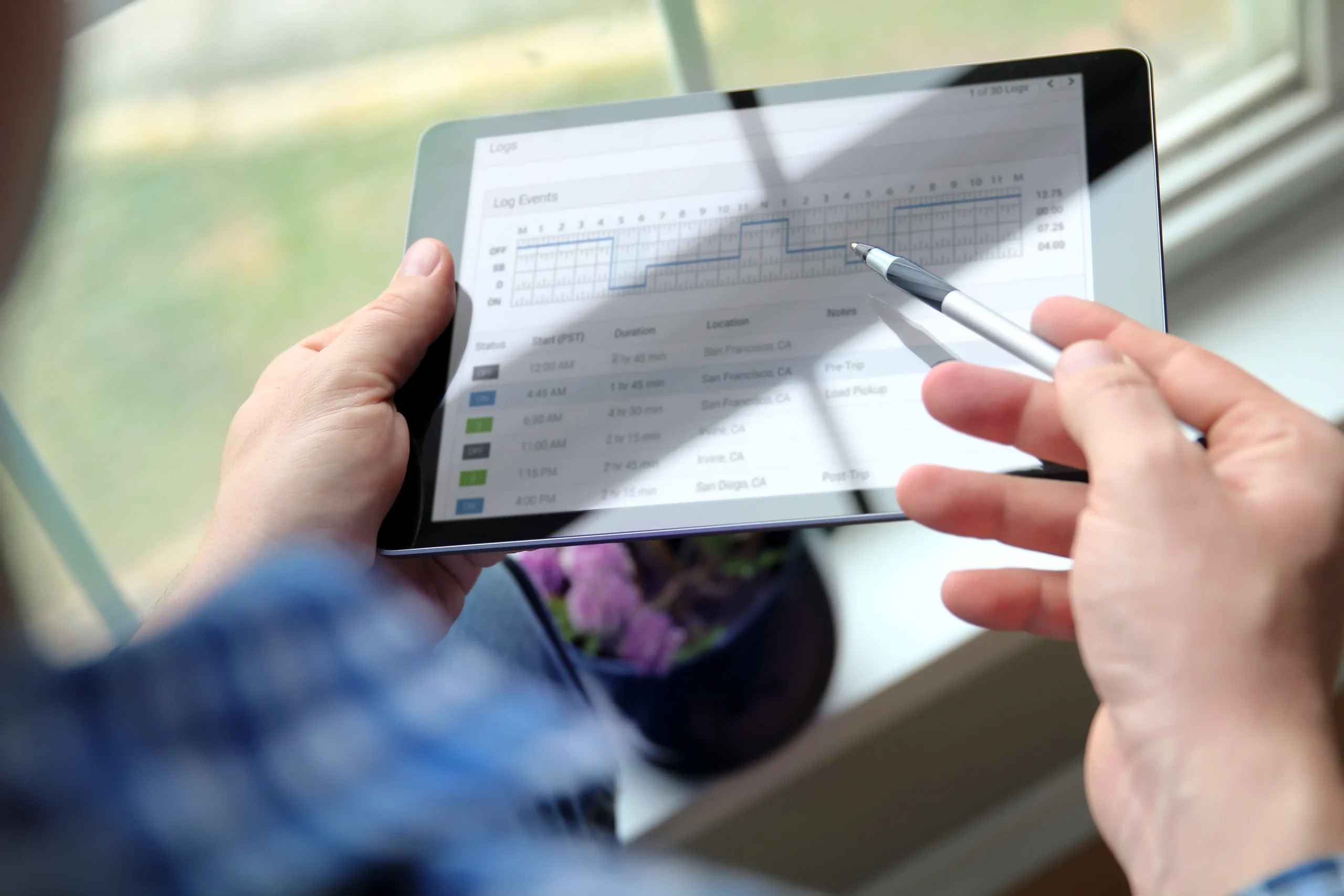 Person reviewing electronic driver logs on a tablet for Canada Hours of Service compliance.