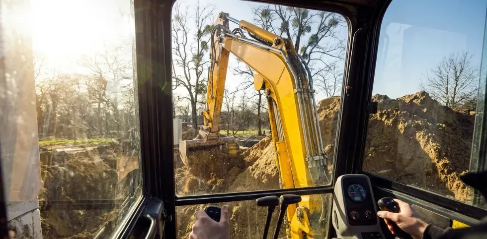 Mini excavator using hydraulic breaker with trained operator following stability and safety procedures. 