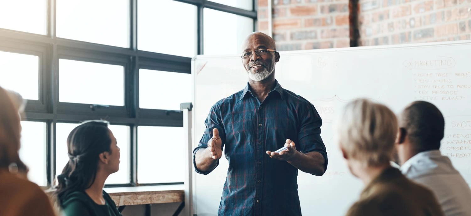 Senior business man doing presentation, planning and talking in a meeting, seminar or training workshop in a boardroom. Manager sharing ideas and teaching training record management