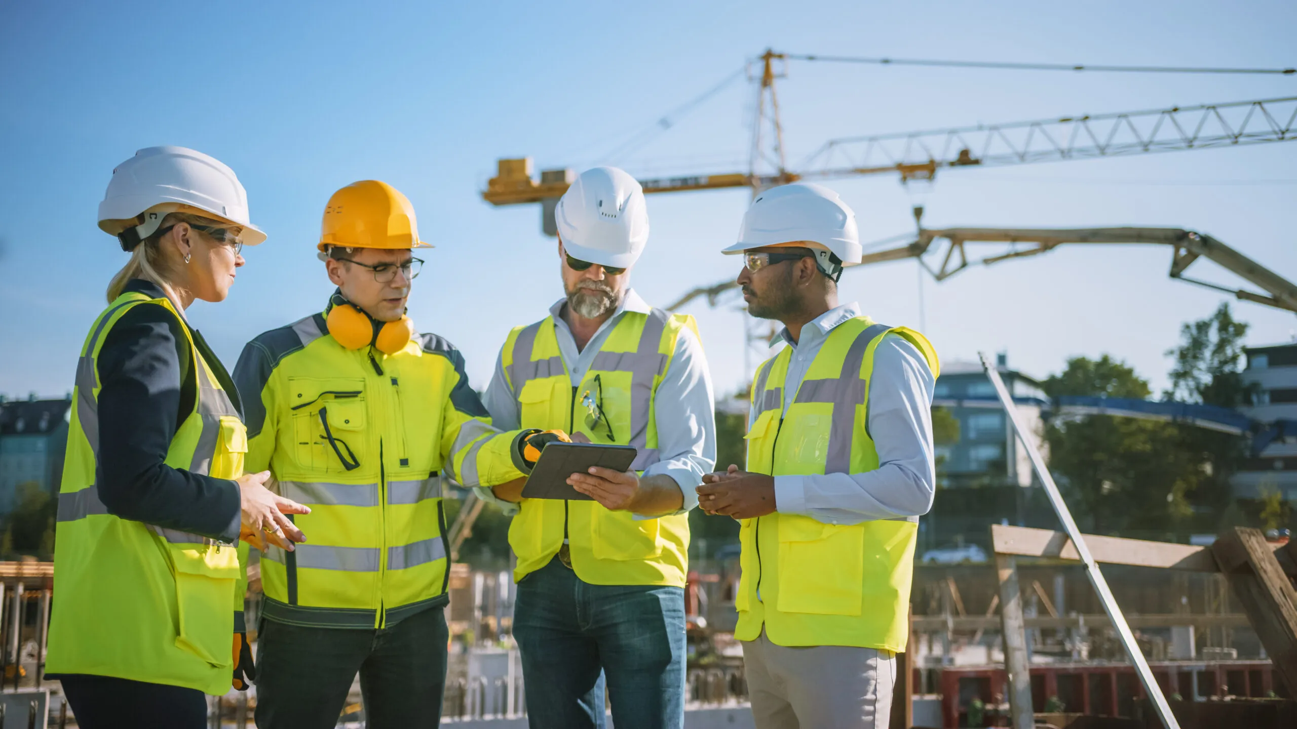 Engineer and construction crew using tablet for digital toolbox talk at outdoor jobsite.