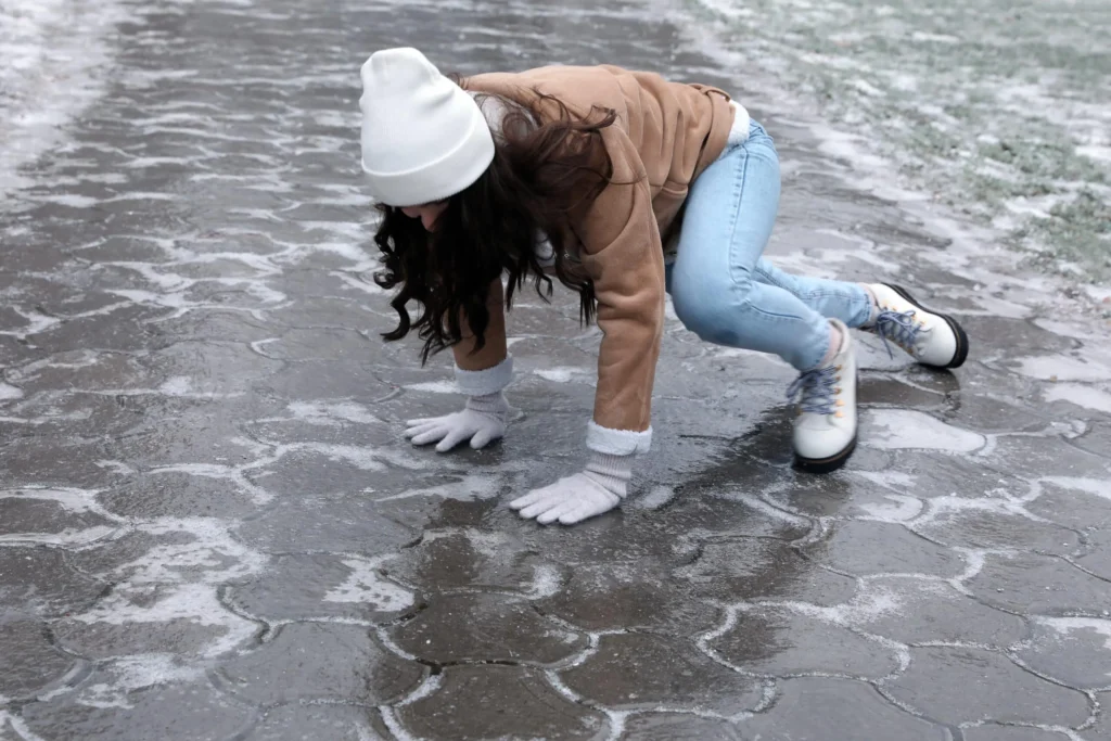 Same‑level fall on a slick surface caused by hidden ice during winter conditions.