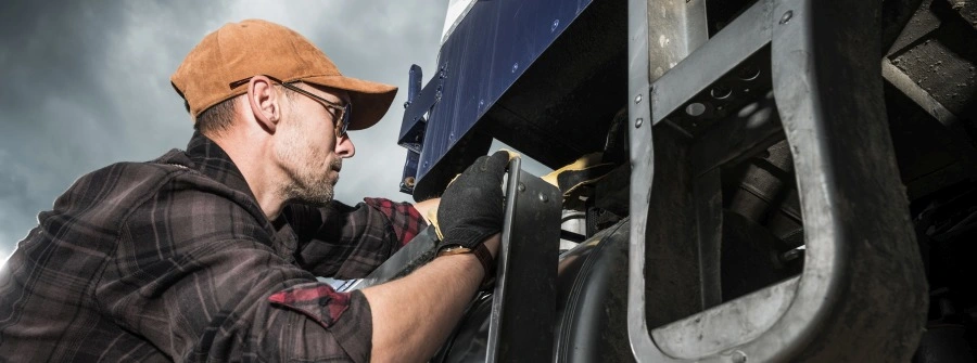 Semi Truck Driver in His 40s Checking Vehicle Elements Near Fuel Tank for truck pre trip inspection form. 