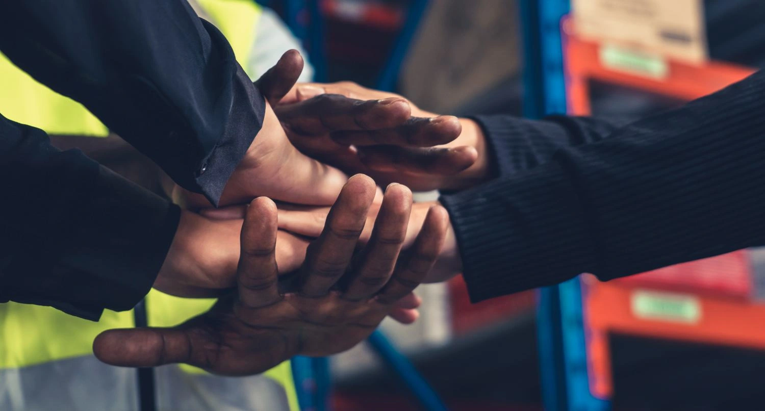 Factory workers stacking hands together in warehouse or storehouse . Logistics , supply chain and warehouse business concept .