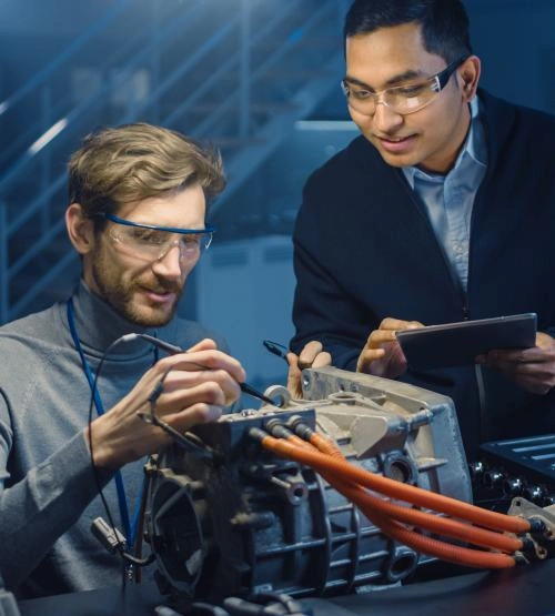 Two Professional Automotive Engineers with a Tablet Computer and Inspection Tools are Having a Conversation While Testing an Electric Engine in a High Tech Laboratory with a Concept Car Chassis.